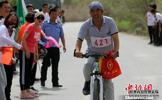 山地自行车赛中年龄最大的王进胜(今年60岁)，骑行一大半路段，观众为他鼓劲加油。　王小军 摄