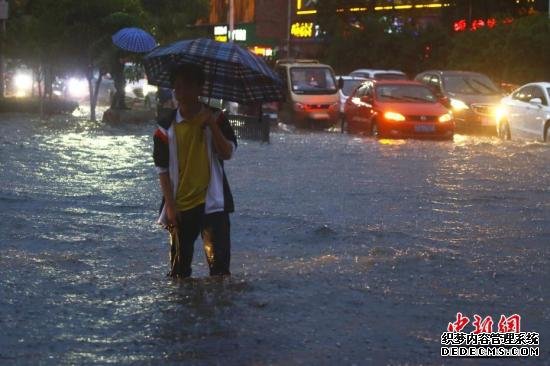 5月25日，江西省瑞昌市出现短时强降水天气，当日17时至19时，两小时内降雨量高达54.8毫米，局部降水71.5毫米，城区部分路段积水严重，市民在雨中艰难出行。/p中新社发 魏东升 摄