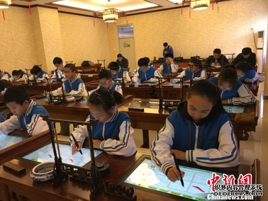 图为小学生正在使用智能书法系统练习写书法。(资料图) 林鹏 摄