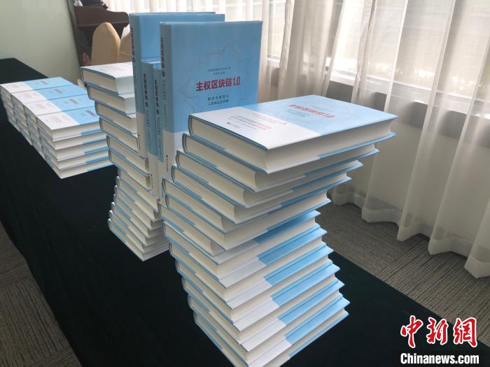 图为仪式现场展示的《主权区块链1.0：秩序互联网与人类命运共同体》。　张伟 摄